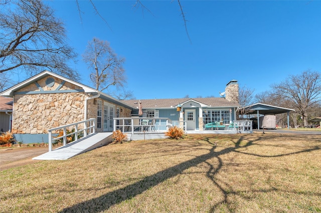 back of house with a carport, a yard, french doors, and a chimney