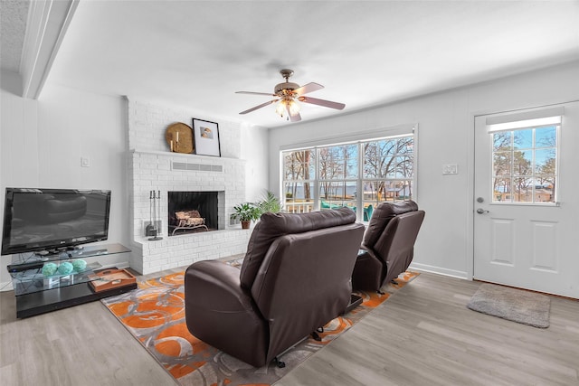 living room featuring a fireplace, plenty of natural light, wood finished floors, and ceiling fan