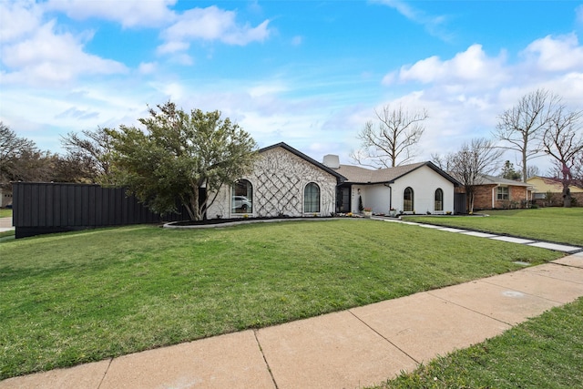 view of front of house featuring a front lawn, fence, stone siding, and a chimney