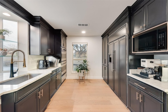 kitchen with light countertops, visible vents, black microwave, and a sink