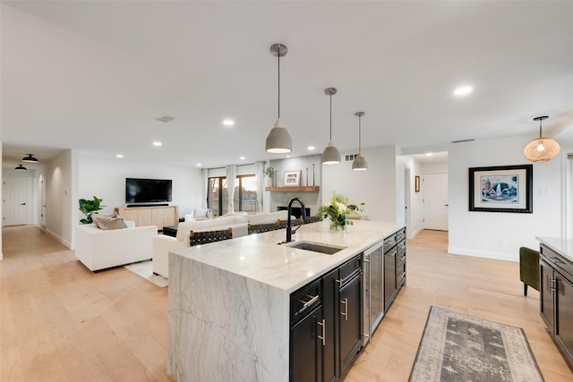 kitchen featuring a sink, light stone counters, recessed lighting, and light wood finished floors