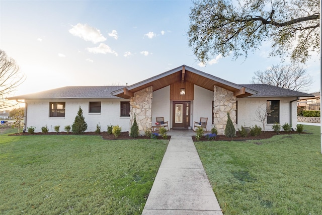 view of front facade featuring stone siding, a front yard, and a shingled roof