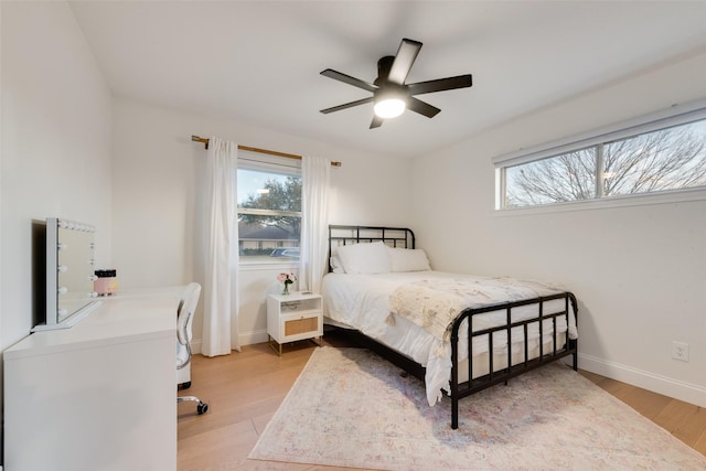 bedroom with multiple windows, light wood-type flooring, and baseboards