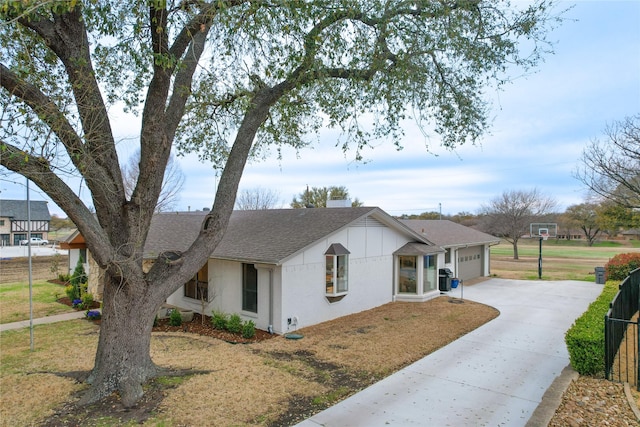 view of front of house with stucco siding, driveway, fence, roof with shingles, and an attached garage