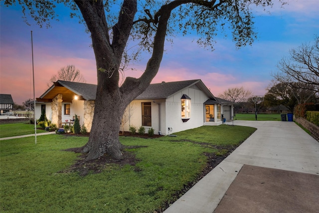 view of front of home with a yard, stone siding, and driveway