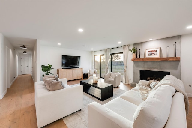 living area with a high end fireplace, recessed lighting, baseboards, and light wood finished floors