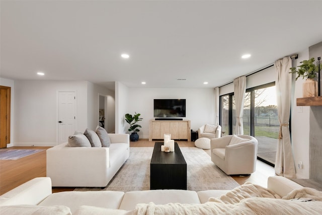 living room with recessed lighting, baseboards, and light wood finished floors