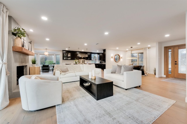 living room featuring a large fireplace, recessed lighting, and light wood-type flooring