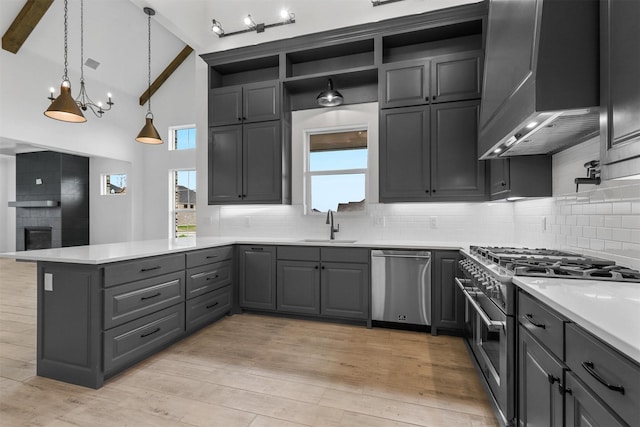 kitchen with beamed ceiling, light countertops, appliances with stainless steel finishes, a peninsula, and a sink