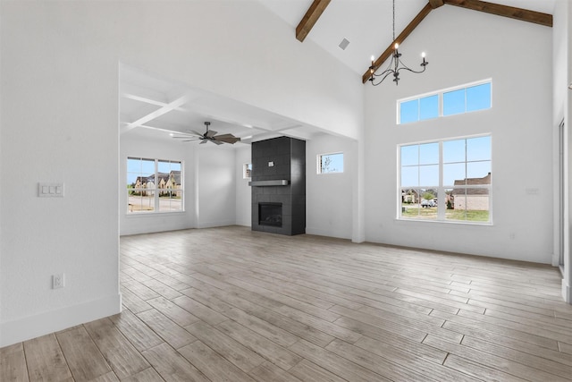 unfurnished living room with visible vents, beam ceiling, ceiling fan with notable chandelier, wood finished floors, and a fireplace