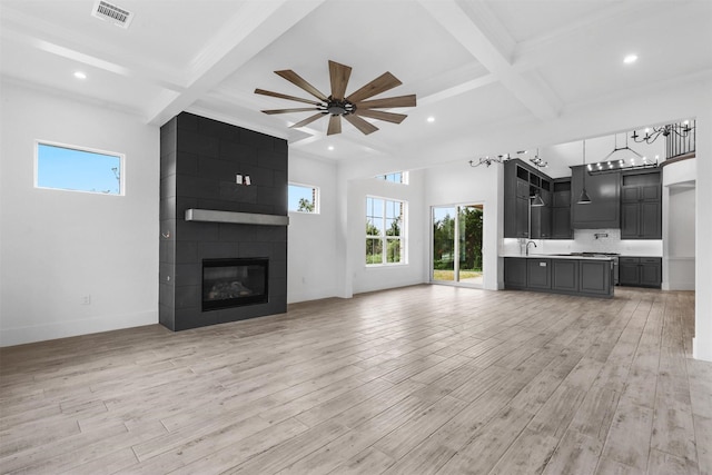 unfurnished living room with light wood finished floors, baseboards, beam ceiling, coffered ceiling, and a sink