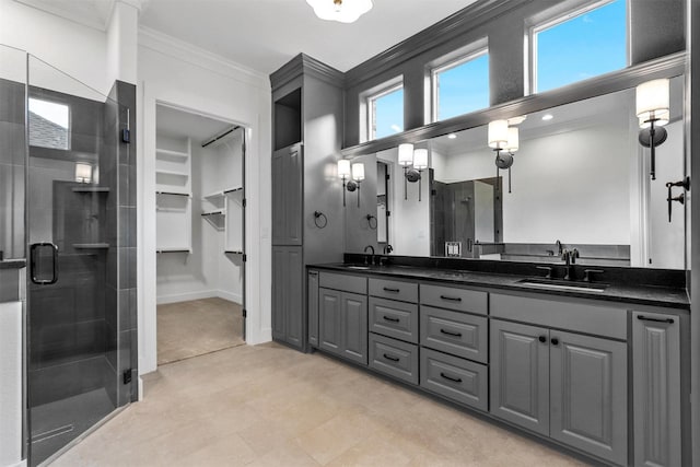 bathroom featuring a sink, a shower stall, crown molding, and double vanity