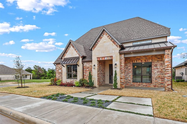 view of front of home with brick siding, a front lawn, metal roof, stone siding, and a standing seam roof