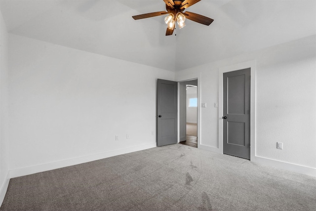 interior space with vaulted ceiling, carpet flooring, a ceiling fan, and baseboards