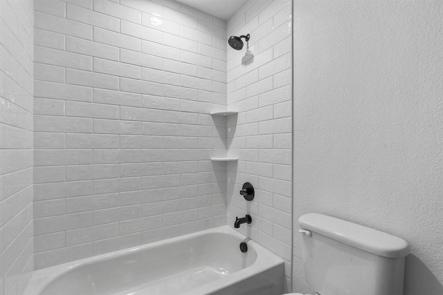 bathroom featuring tub / shower combination, toilet, and a textured wall