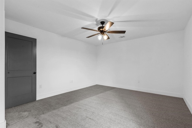 carpeted spare room with visible vents, baseboards, and ceiling fan