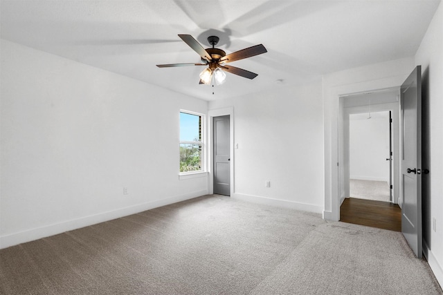 carpeted empty room featuring attic access, baseboards, and ceiling fan