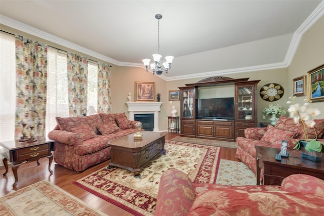 living area with a chandelier, vaulted ceiling, ornamental molding, a fireplace, and wood finished floors