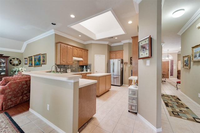 kitchen featuring under cabinet range hood, light tile patterned floors, freestanding refrigerator, and ornamental molding