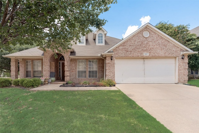 view of front facade with brick siding, a front yard, an attached garage, and driveway