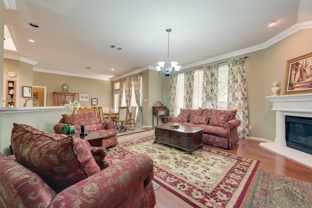 living room with a notable chandelier, visible vents, crown molding, and wood finished floors