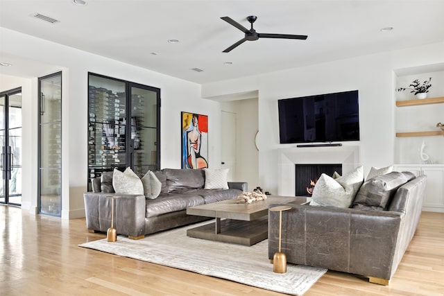 living area featuring visible vents, a lit fireplace, recessed lighting, wood finished floors, and a ceiling fan