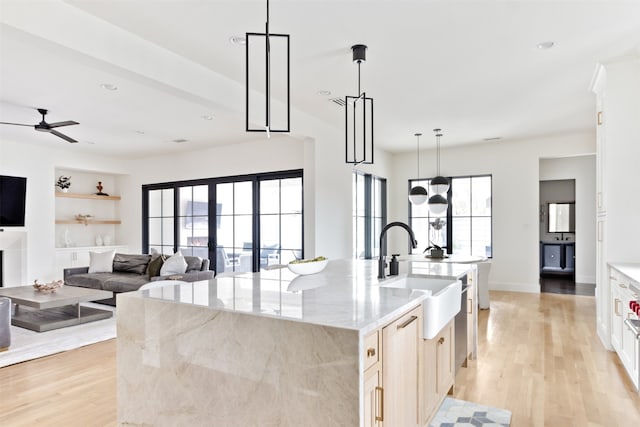 kitchen with a sink, plenty of natural light, light wood-style flooring, and a large island with sink