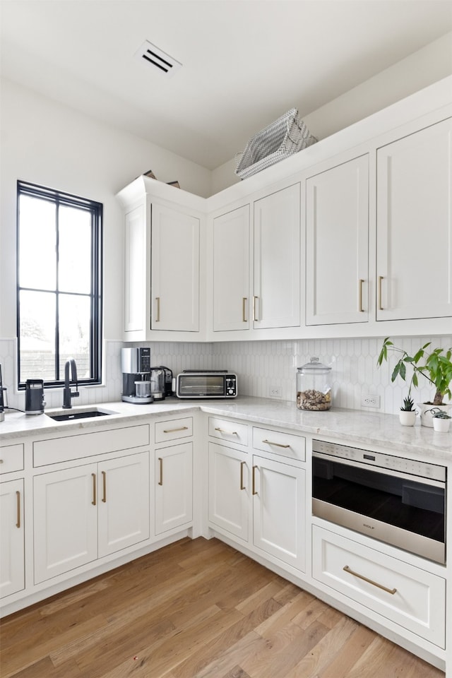 kitchen with white cabinetry, light countertops, visible vents, and a sink