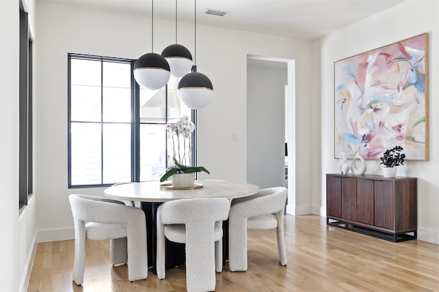 dining area with baseboards, visible vents, and light wood finished floors