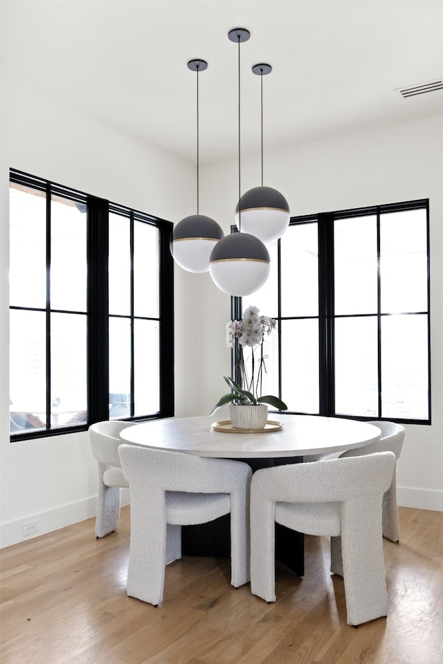 unfurnished dining area with light wood finished floors, visible vents, and baseboards