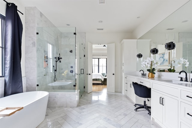 ensuite bathroom featuring double vanity, a freestanding bath, a sink, a shower stall, and connected bathroom