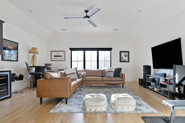 living room featuring a raised ceiling, a ceiling fan, light wood-style floors, and baseboards