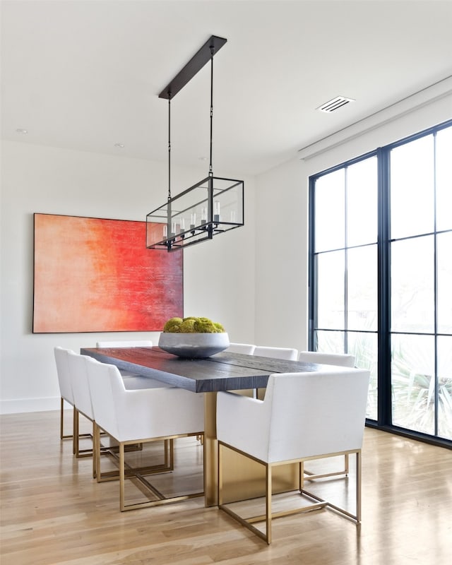 dining area featuring a notable chandelier, visible vents, baseboards, and light wood-style floors