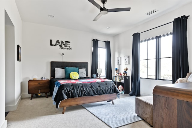 bedroom with visible vents, multiple windows, light colored carpet, and ceiling fan