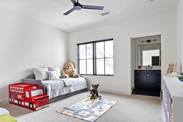 bedroom featuring visible vents, a sink, ensuite bath, baseboards, and light colored carpet