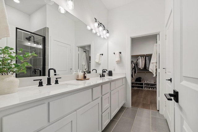 bathroom featuring double vanity, tile patterned flooring, a shower stall, and a sink