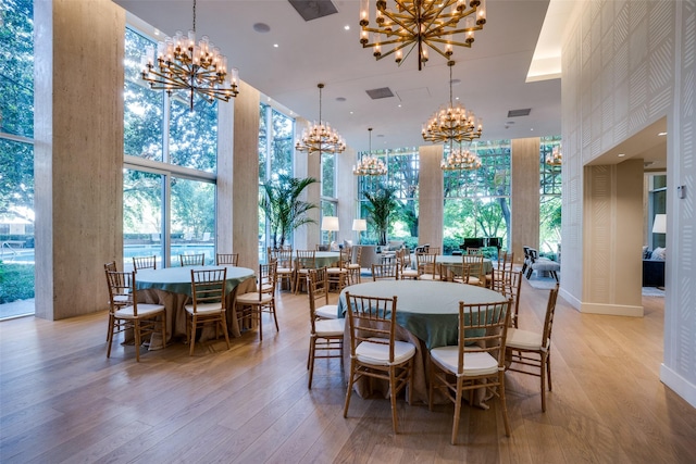 dining space with light wood finished floors, a towering ceiling, and a notable chandelier
