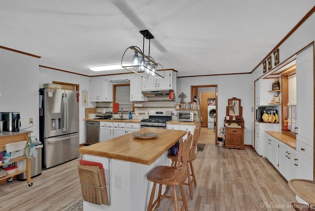 kitchen with light wood-type flooring, appliances with stainless steel finishes, white cabinets, and crown molding