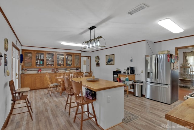 kitchen featuring visible vents, light wood finished floors, stainless steel fridge with ice dispenser, crown molding, and butcher block counters