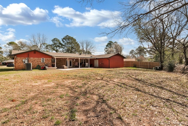 rear view of house with brick siding, fence, a lawn, cooling unit, and a patio