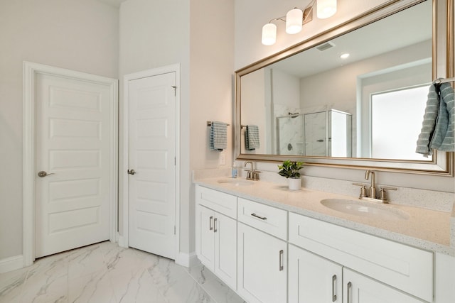 bathroom with double vanity, marble finish floor, a shower stall, and a sink