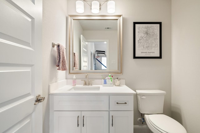 half bathroom with vanity, toilet, and visible vents