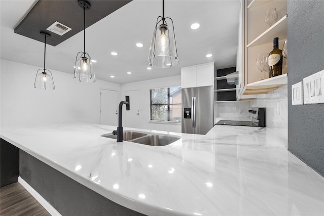 kitchen featuring light stone countertops, open shelves, a sink, range, and stainless steel fridge