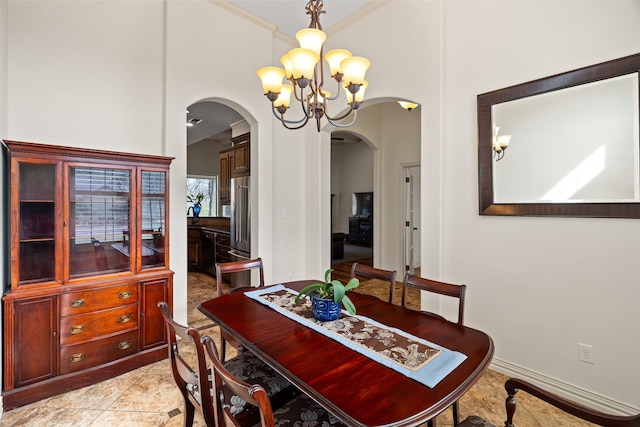 dining area with arched walkways, a chandelier, baseboards, and ornamental molding