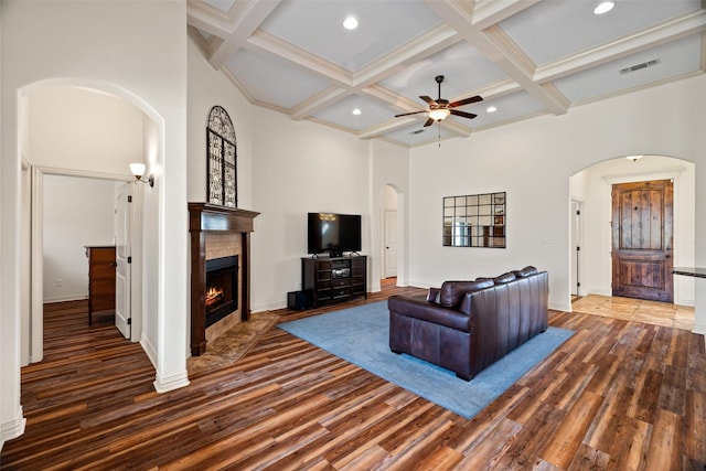 living area featuring visible vents, a ceiling fan, wood finished floors, arched walkways, and a tile fireplace