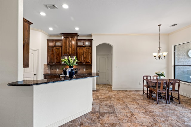 kitchen with tasteful backsplash, visible vents, glass insert cabinets, crown molding, and arched walkways