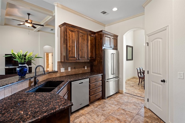 kitchen featuring tasteful backsplash, dishwashing machine, high quality fridge, arched walkways, and a sink