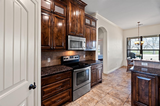 kitchen with ornamental molding, tasteful backsplash, arched walkways, appliances with stainless steel finishes, and glass insert cabinets