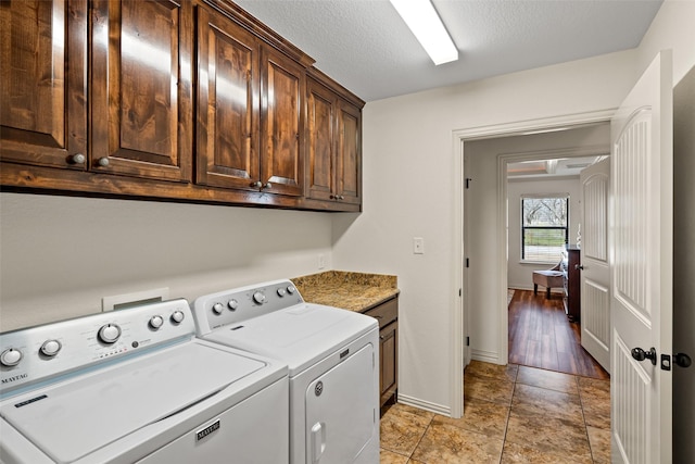 laundry room featuring cabinet space, a textured ceiling, baseboards, and separate washer and dryer