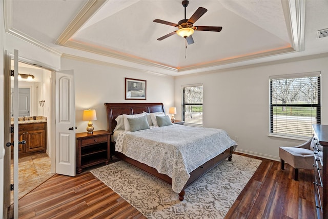 bedroom with visible vents, a tray ceiling, and dark wood-style flooring